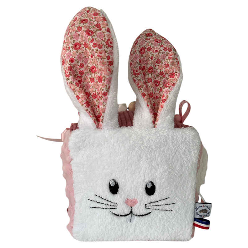 cube d'activité sensoriel pour bébé fille de couleur rose vec lapin blanc et diférentes activités sonores
